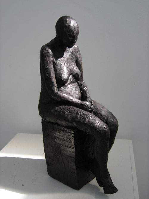 Siddende kvinde på høj klods