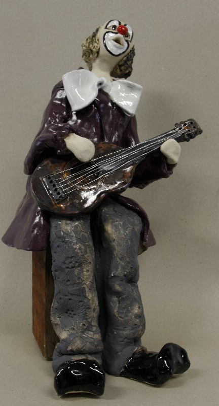 Siddende klovn med guitar